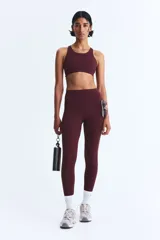 Top deportivo color vino tinto, de tejido funcional con tecnología ShapeMove™ y DryMove™, corte ajustado, escote cuadrado al frente y espalda nadadora en malla con cut-out. Presenta copas forradas con relleno extraíble y breteles anchos ajustables.