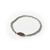 Pulsera elástica de cuentas plateadas con dije central en forma de ojo con textura brillante color bronce.