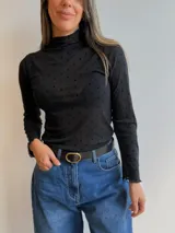 Remera de tul de manga larga con estampado de lunares negros sobre fondo blanco. Presenta cuello y bordes con terminación ondulada.