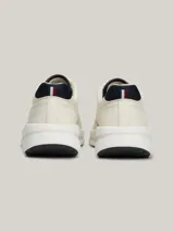 Zapatillas Tommy Hilfiger de cuero color blanco con detalles en azul marino. Presentan cordones azul marino, suela gruesa blanca y logo de la marca en el lateral.