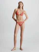 Brasier triangular sin aros, confeccionado en encaje floral semitransparente de color coral/naranja. Presenta un cierre metálico en la parte frontal y tirantes finos ajustables que se cruzan en forma de 'X' en la espalda.