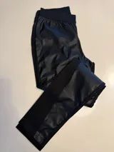 Pantalón ajustado negro con frente de cuerina elástica y parte trasera de gabardina con spandex, cintura elástica y bandas laterales de tela.