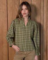 Blusa de algodón con estampa a cuadros en tonos verdes y beige, de manga larga abullonada con puños con volados, escote en V y cuello alto con volados fruncidos.