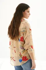 Camisa blanca de tela liviana y ligeramente arrugada, con bordados de motivos marinos en tonos azul, verde y ocre. Presenta cuello camisero, abotonadura frontal y mangas tres cuartos.