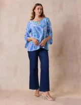 Blusa de gasa estampada con motivos paisley en tonos azules, marca Ruby Rd. Tiene cuello redondo con escote en V y aplique metálico. Presenta una sobre capa delantera y terminación asimétrica. Las mangas son 3/4 y amplias.