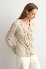Blusa de encaje beige con escote en V y volados frontales, de manga larga.