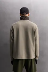 Camiseta relaxed fit de color verde militar, confeccionada en tejido con estructura waffle. Tiene cuello redondo, manga larga con puño elástico y un bolsillo plastrón con cierre de cremallera en el pecho.