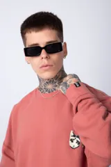 Buzo de corte oversize confeccionado en tela friza, con cuello redondo y puños acanalados. Presenta un diseño minimalista con un pequeño bordado en el pecho y un diseño estampado en la espalda.