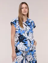 Camisa de manga corta confeccionada en rayón y poliéster, con estampado floral en tonos azules, negros y blancos, cuello camisero clásico y cierre frontal de botones.