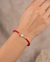 Pulsera de plata 925 con cuentas de cristal facetado en color rojo, adornada en el centro con una perla de río blanca rodeada de pequeñas esferas plateadas.