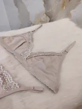 Conjunto de lencería compuesto por un corpiño triangular y una bombacha tipo colaless, ambos confeccionados en algodón color nude con delicados detalles de encaje en los bordes.