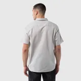 Camisa de manga corta con cuello clásico, cierre frontal de botones y un bolsillo en el pecho. Presenta un diseño de corte regular con textura natural.