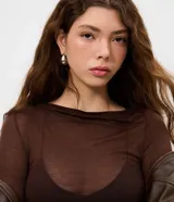 Blusa de manga larga con transparencia, confeccionada en viscosa y elastano. Presenta un diseño ajustado al cuerpo, cuello redondo y textura sutil, ideal para usar en capas.