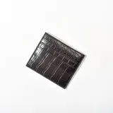 Tarjetero negro con textura símil cuero de cocodrilo, con múltiples ranuras para tarjetas.