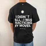 Remera negra de corte regular con estampa gráfica en la espalda que incluye un sol y la frase 'I didn't fall - I was practicing my moves'.