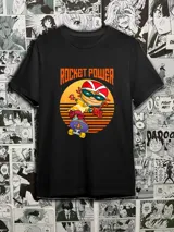 Remera negra con estampado de Otto Rocket de la serie animada Rocket Power, sobre una patineta y un fondo de puesta de sol.