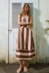 Vestido midi sin mangas, con escote en V y detalle de lazada frontal. Presenta un diseño de rayas verticales en tonos rosado y marrón, con un panel inferior de rayas horizontales.