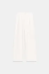 Pantalón blanco de tejido rústico, tiro alto con cintura elástica y cordón ajustable, y pierna ancha.