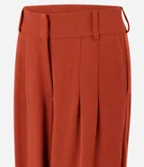 Pantalón balloon de piqué color terracota, con cintura estructurada, pinzas delanteras, pasacintos, piernas amplias y dobladillos elásticos.
