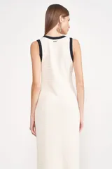 Vestido midi de punto color crema, con escote cuadrado, breteles anchos con ribete negro y abertura lateral en la falda con ribete negro.