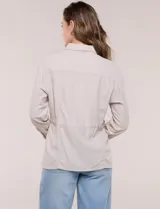 Sobrecamisa beige de lino liviano, con cuello camisero, cierre frontal de botones carey y bolsillos en el pecho. Cuenta con cordón ajustable en la cintura y mangas largas.