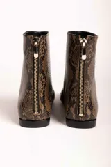 Botas cortas de gamuza color marrón, con punta cuadrada y cierre lateral. Diseño minimalista con costura central vertical.