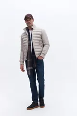 Campera puffer de nylon color beige, con diseño minimalista, cuello alto, cierre frontal y puños elásticos. Presenta logo de la marca bordado en el pecho.