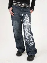 Pantalón de jean azul oscuro con lavado localizado y estampado serigrafiado en color blanco de un ave fénix en la pierna izquierda. Presenta un corte recto y tiro bajo.