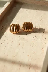 Aros tipo botón dorados con diseño ondulado.