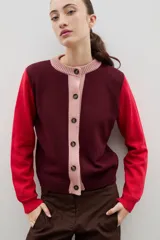 Saco de punto con diseño color block, presenta cuerpo en color bordó, mangas en color rojo y tapeta frontal con cuello redondo en color rosado. Posee cierre frontal con botones y puños acanalados.