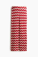 Pantalón tejido en punto jacquard estilo crochet, con diseño de rayas en zigzag de colores rojo y blanco, de tiro medio y piernas amplias.