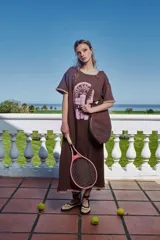 Vestido marrón holgado con estampado frontal y mangas cortas con terminación de crochet. Incluye una funda de raqueta de tenis y una raqueta de tenis rosa.