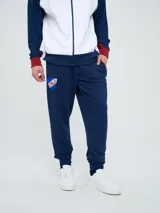 Pantalón deportivo azul marino con puños elásticos en los tobillos, bolsillos laterales con cierre, escudo del Club Nacional de Football en una pierna y logo de Umbro en la otra.