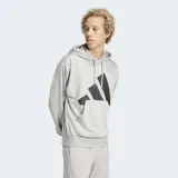 Canguro Adidas con capucha y cordones ajustables, confeccionado en felpa francesa color gris. Presenta un diseño de hombros caídos, ajuste holgado y un gran logo de las 3 Barras de Adidas estampado en color negro en el pecho.