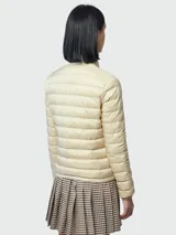 Campera corta acolchada Moncler modelo Lans, color beige, con cuello alto, cierre frontal con tirador personalizado, bolsillos laterales y logo de la marca en la manga izquierda.