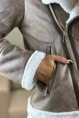 Campera tipo gamulán de cuero sintético negro con interior y solapas de corderito blanco. Presenta cierre frontal cruzado y bolsillos laterales con cierre.