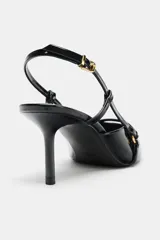 Zapato de tacón fino con acabado en punta, confeccionado en material sintético brillante. Presenta un diseño de tiras cruzadas en el empeine con detalles de hebillas metálicas y una tira trasera ajustable con cierre de hebilla.