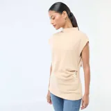 Sweater sin mangas color beige de tejido de punto, con cuello alto y detalle de hebilla metálica en forma de corazón en el lateral de la cintura.