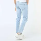 Pantalón de jean corte slim, color azul claro con efecto lavado, cierre frontal con botón y cremallera, y bolsillos laterales y traseros.