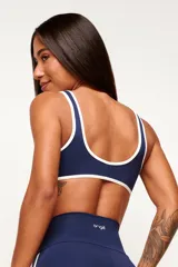 Top deportivo de poliamida color azul marino, de modelado slim y ajuste ceñido al cuerpo. Presenta escote redondo y tiras en color blanco contrastante que recorren los bordes superior e inferior, con el logo de la marca estampado en el centro del pecho.