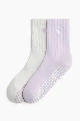 Pack de dos pares de medias deportivas de caña acanalada, una en color gris melange y otra en color lila, con suela antideslizante de puntos de goma y detalle bordado de moño.