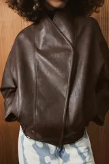 Chaqueta bomber de efecto piel en color marrón oscuro, con cuello subido, cierre frontal cruzado con botones a presión, bolsillos laterales y bajo elástico.
