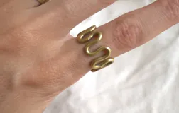 Anillo de bronce dorado con diseño de ondas.