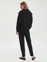 Pantalón negro de tejido DoubleSoft, corte ajustado con puños enrollados, pinzas delanteras y traseras, y bolsillos con forma.