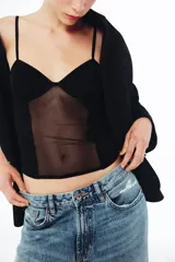 Corsé de escote en pico con tirantes finos, confeccionado en una combinación de tejido opaco y paneles de tul transparente, con costuras visibles a tono.