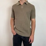 Chomba de tejido de punto color marrón, con cuello polo y manga corta. Presenta una textura acanalada y un diseño clásico de ajuste regular.