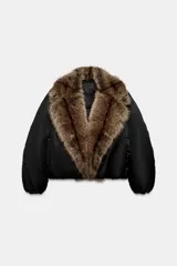 Chaqueta bomber negra de corte corto y diseño abullonado, con cuello de solapa amplio en pelo sintético marrón. Cuenta con mangas largas y cierre frontal.