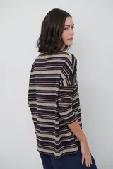 Remera de manga larga con diseño de rayas horizontales en tonos marrones, beige y rojizos. Presenta cuello redondo y un detalle bordado en el pecho.