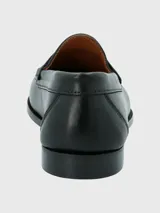Zapato tipo mocasín de cuero negro con diseño clásico, costuras visibles en la puntera y detalle de antifaz en el empeine.