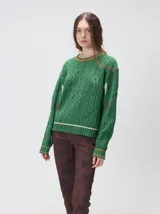 Sweater de tejido de punto trenzado en color marrón, con cuello redondo, puños y ruedo acanalados. Presenta detalles de franjas en color naranja en el cuello y el ruedo, además de apliques de rombos en tonos naranja y verde en las mangas.